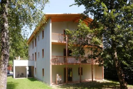 Ein Haus mit einem markanten Balkon an der Vorderseite und einem zusätzlichen Balkon an der Seite.