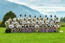 Eine Gruppe von Menschen in traditioneller bayerischer Kleidung lächelt und posiert gemeinsam für ein Foto.
