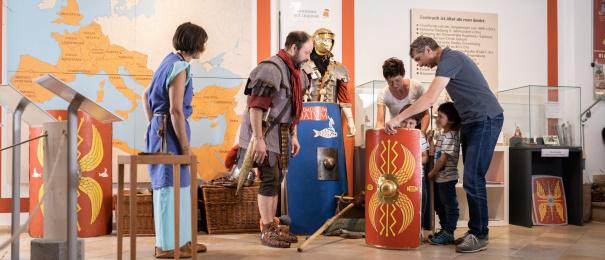 Visitors examine ancient Roman artifacts displayed in a museum, showcasing historical culture and craftsmanship.