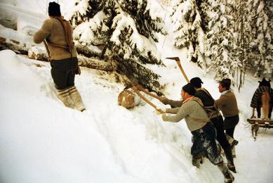Men in winter clothing pull a sled through deep snow, showing a winter outdoor activity.